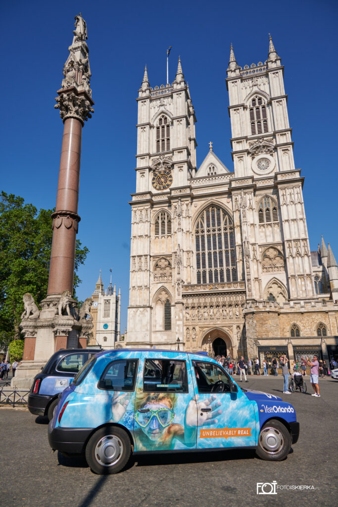 Niebieski samochód a w tele Opactwo Wesminsterskie w Londynie w Anglii. A blue car and Wesminster Abbey in London, England