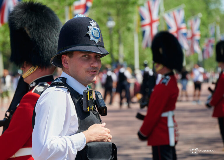 Gwardia królewska i angielski policjant podczas zmiany warty w Londynie w Buckingham Palace i ceremonii „Beating Retreat. The photo sparkle is in London where the Changing of the Guard at Buckingham Palace and the "Beating Retreat" ceremony take place