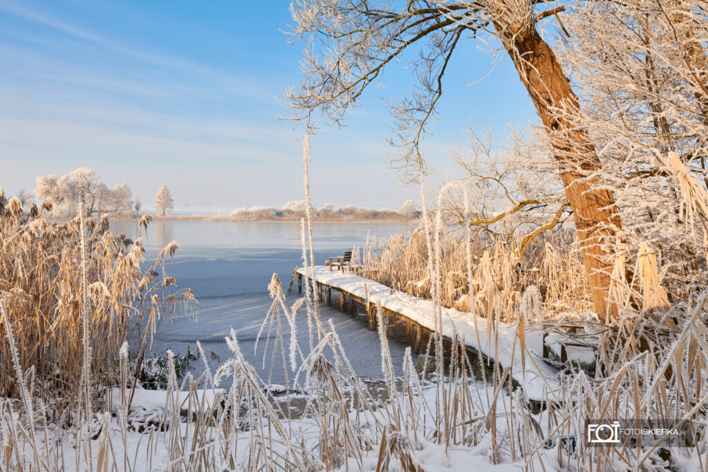 Zima na Mazurach w Polsce w Stanowie. W tle zamarznięte jezioro, ośnieżony pomost