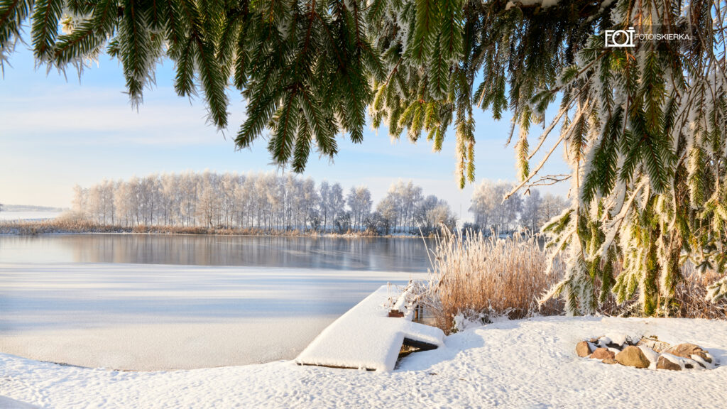 Zima na Mazurach w Polsce w Stanowie. W tle zamarznięte jezioro, ośnieżony pomost