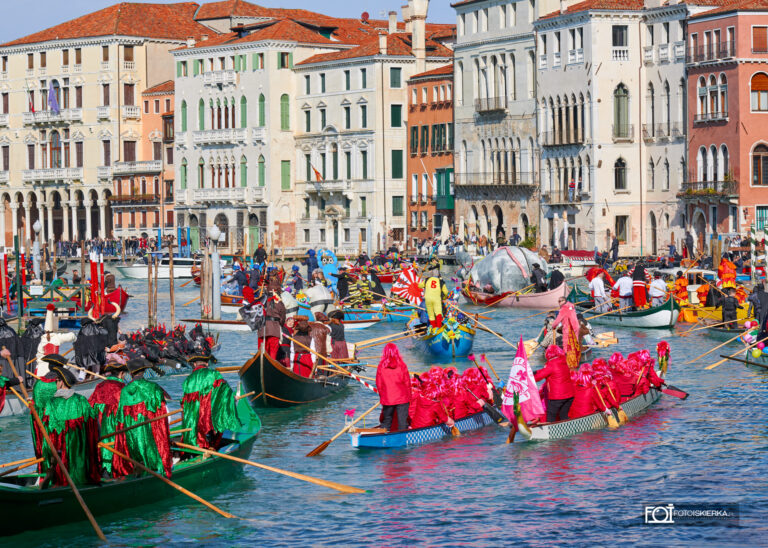 Wodna parada podczas Karnawału w Wenecji – widowiskowy korowód łodzi na Canal Grande. Uczestnicy w fantazyjnych kostiumach i maskach kultywują tradycję voga alla veneta. W oddali widoczna słynna Pantegana, symbolizująca ludowy charakter weneckiego święta Festa Veneziana sull’Acqua.